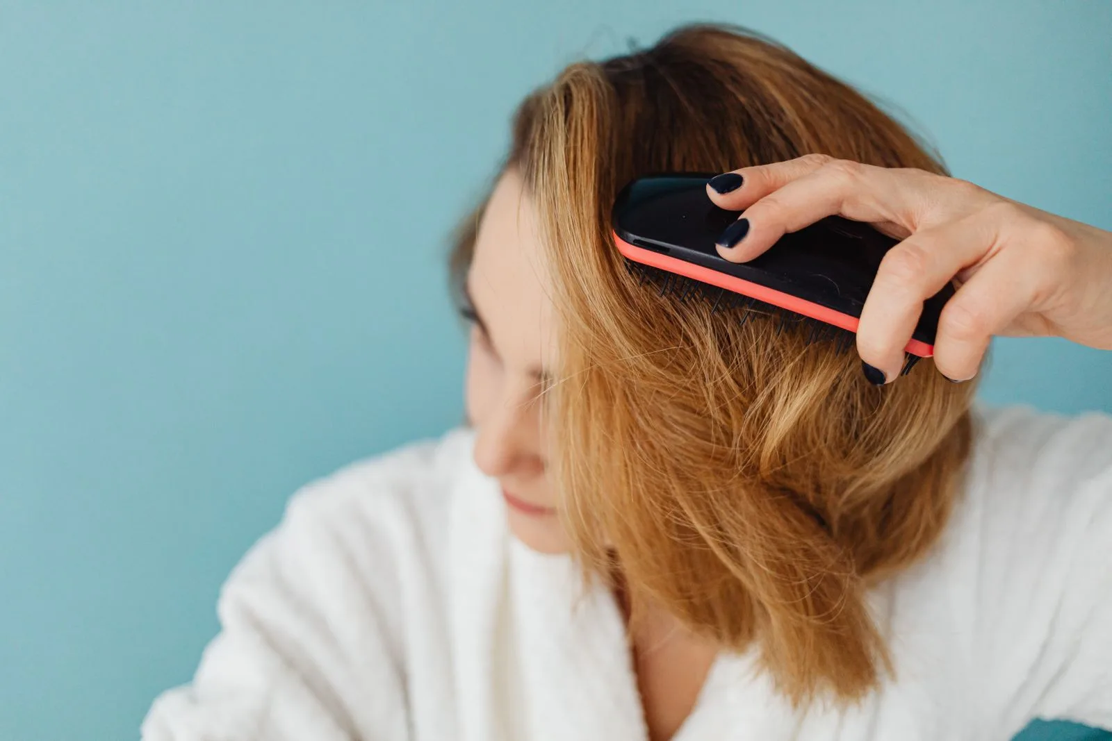Woman brushing her hair at a bathroom mirror, noticing thinning and shedding